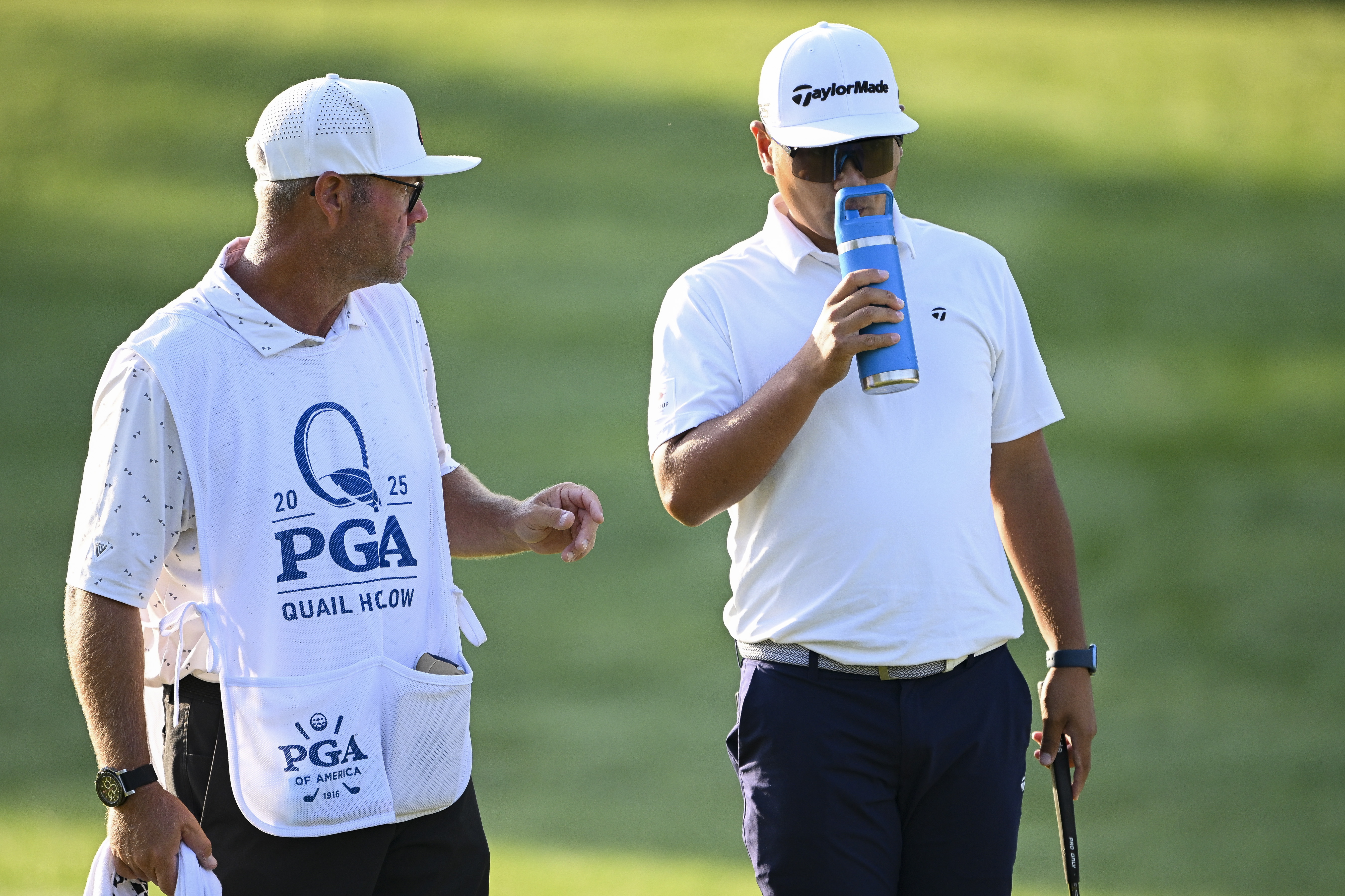Ryo Hisatsune takes a sip of water next to his caddie