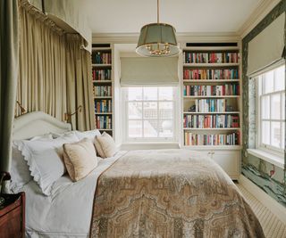 small bedroom with bookshelf lined walls and drapes behind