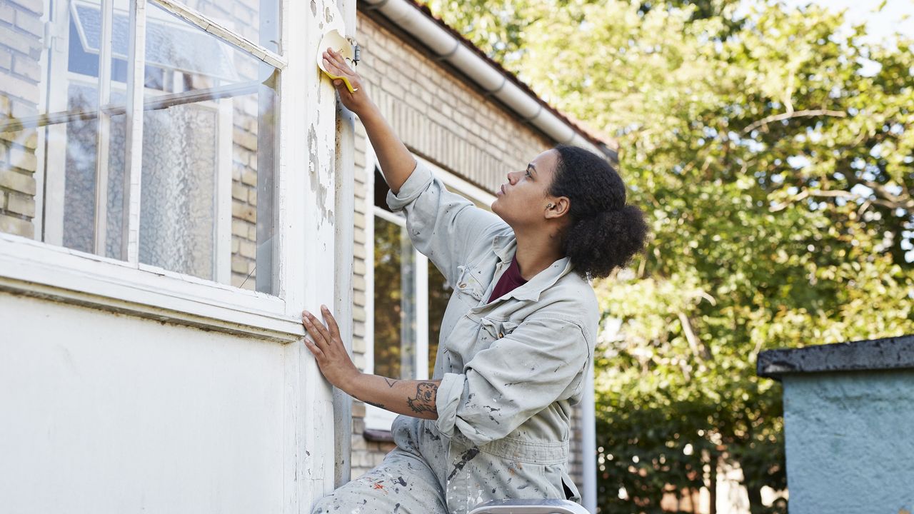 Woman scraping wall during home renovation