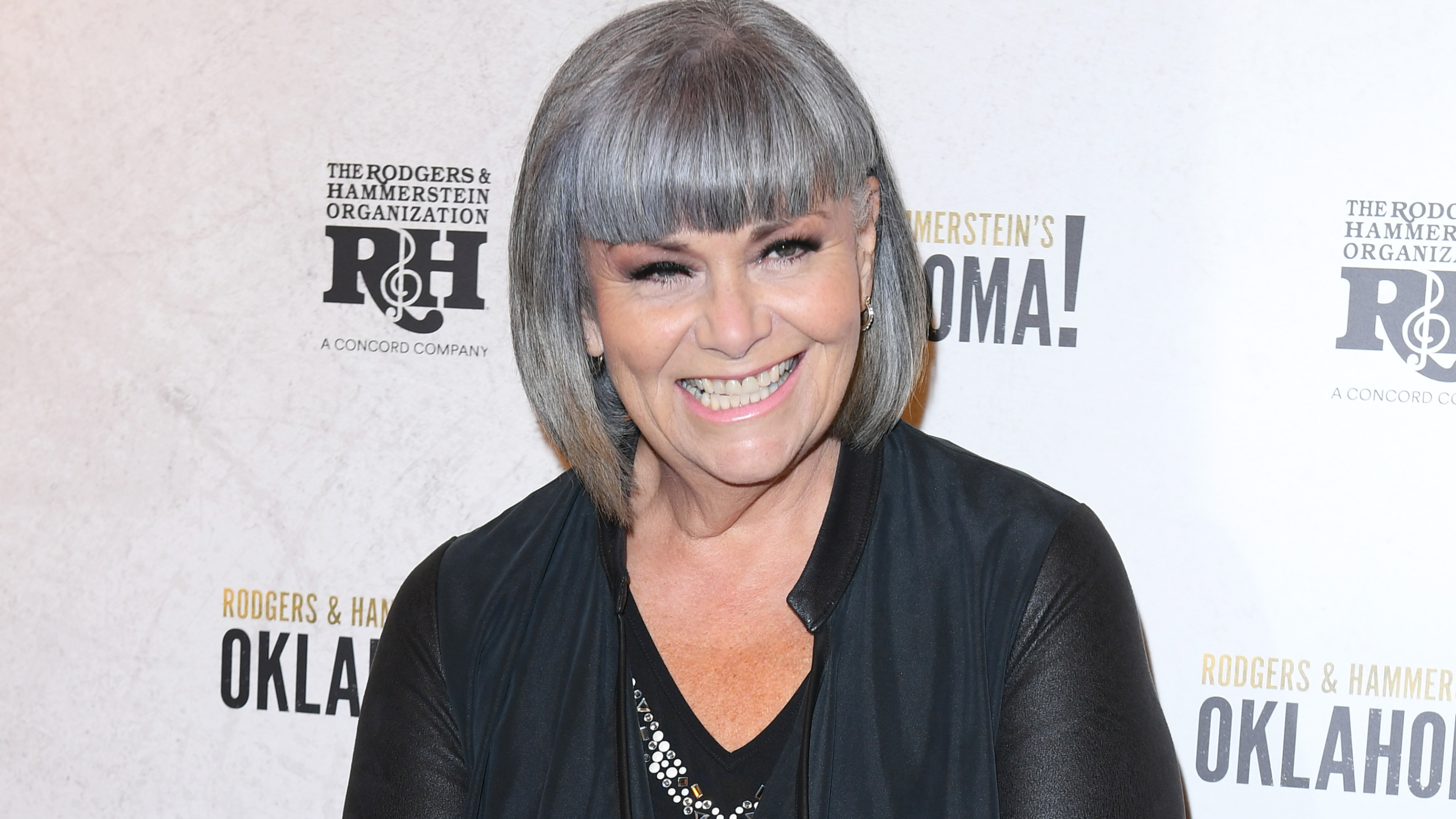 Dawn French in all back smiling on red carpet.
