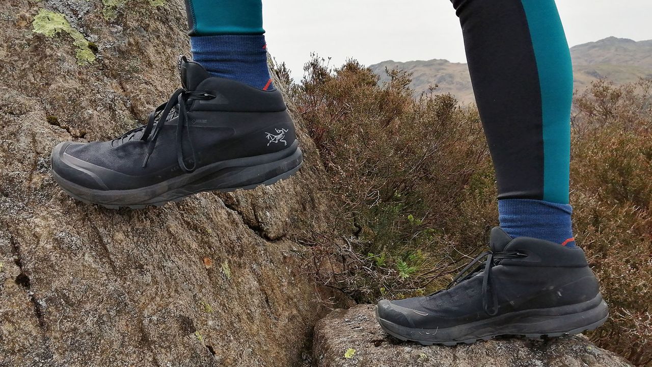 Close up of Arc&#039;Teryx Aerios FL Mid GTX boots worn by a person on rocky ground