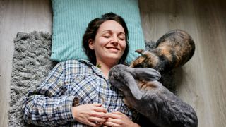 Woman lying on floor with two pet rabbits