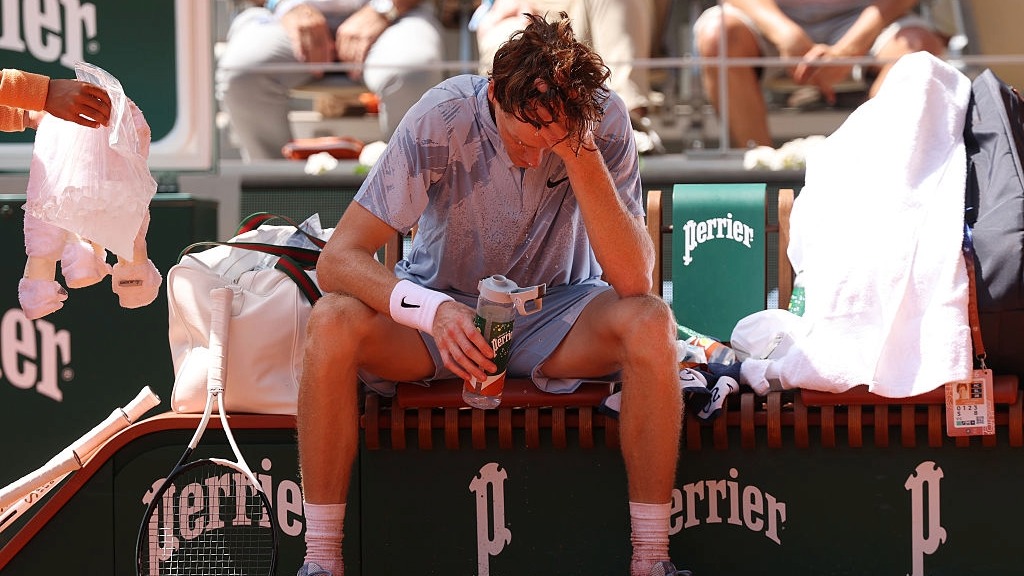 Jannik Sinner puts his head in his hands as he struggles with illness and the heat in losing at the French Open 2026.