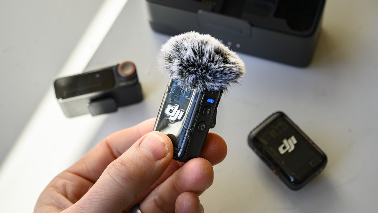 DJI Mic 2 transmitter in the hand with wind shield attached