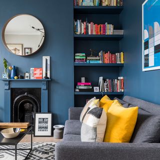 living room with blue wall grey sofa with cushion blue book shelf on wall