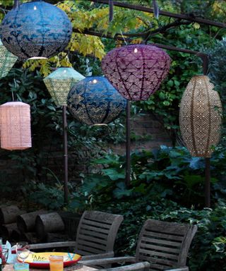 Multicoloured lanterns hanging from trellis over garden table