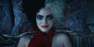 Emma Stone smiles while lying in bed in Cruella.