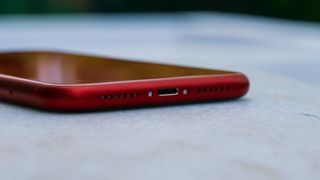 An iPhone XR in red, viewed from the bottom edge