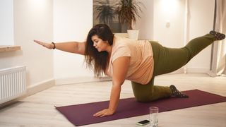 Woman performs bird-dog exercise on exercise mat