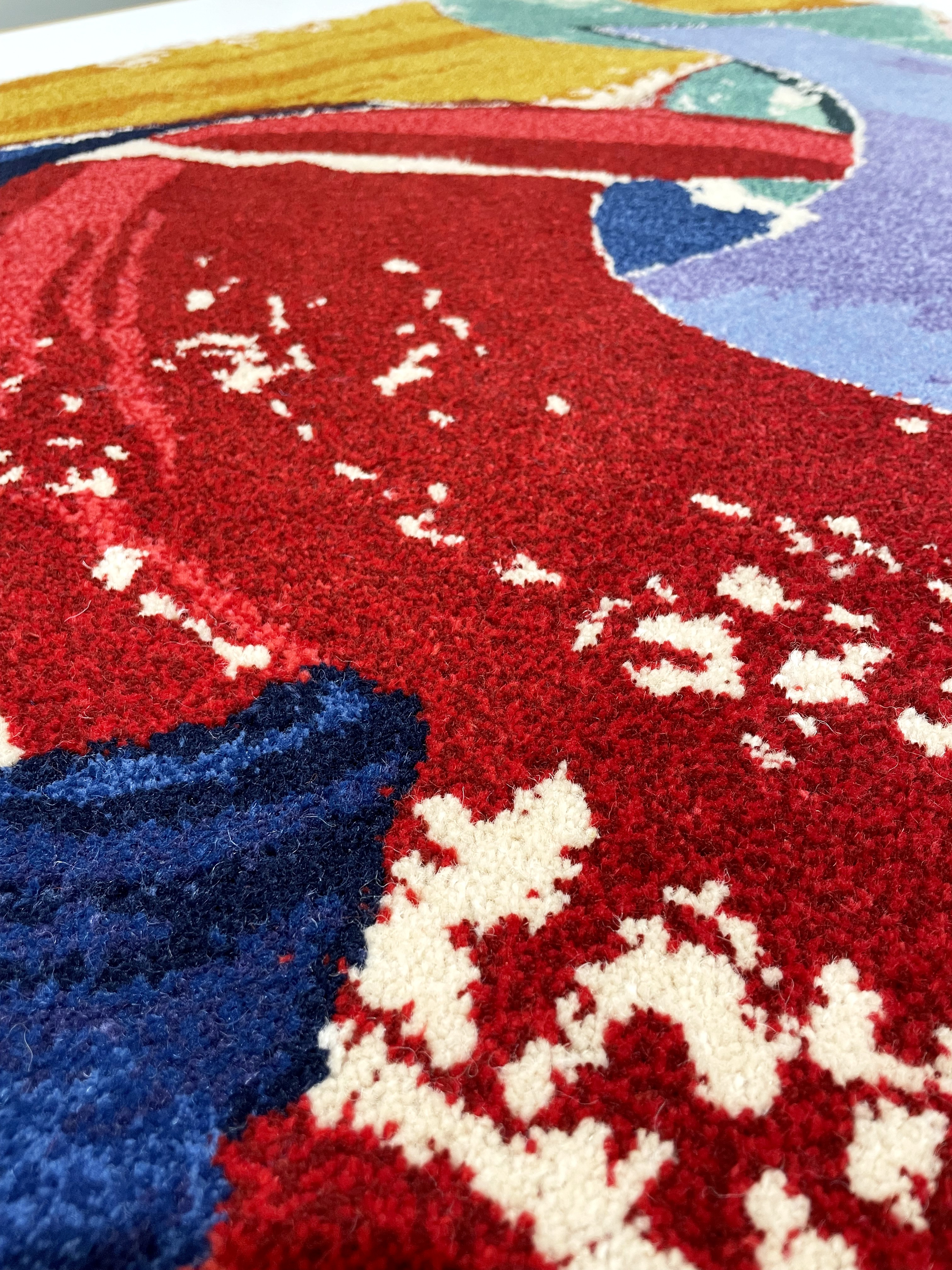 A tufted rug with an abstract design and swathes of cream, red, blue, purple, ochre, and sea green.