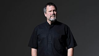 A photograph of Billy Gould stood in front of a black background
