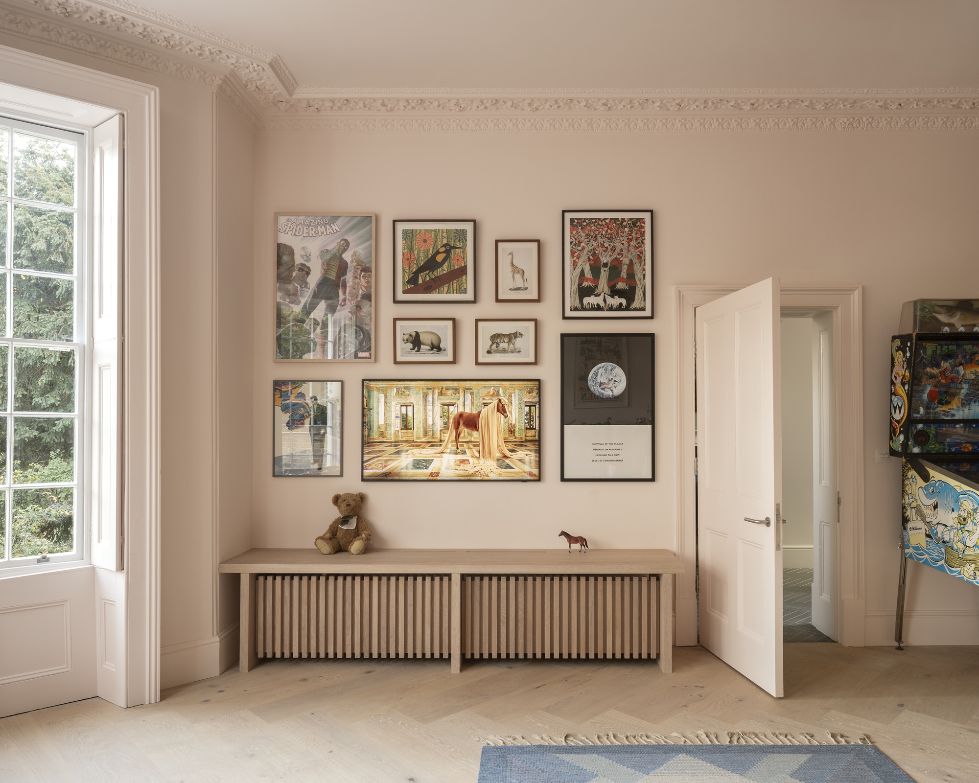 light pink walls with gallery wall, timber benchseat, window, and herringbone floors