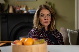Cathy (Stockard Channing) sits at a kitchen table, with a bowl of fruit in front of her
