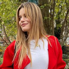 Sabina Socol wears a white T-shirt and jeans with a red coat 