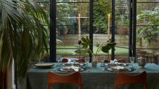 A cool, earthy dinner party set indoors by a garden space