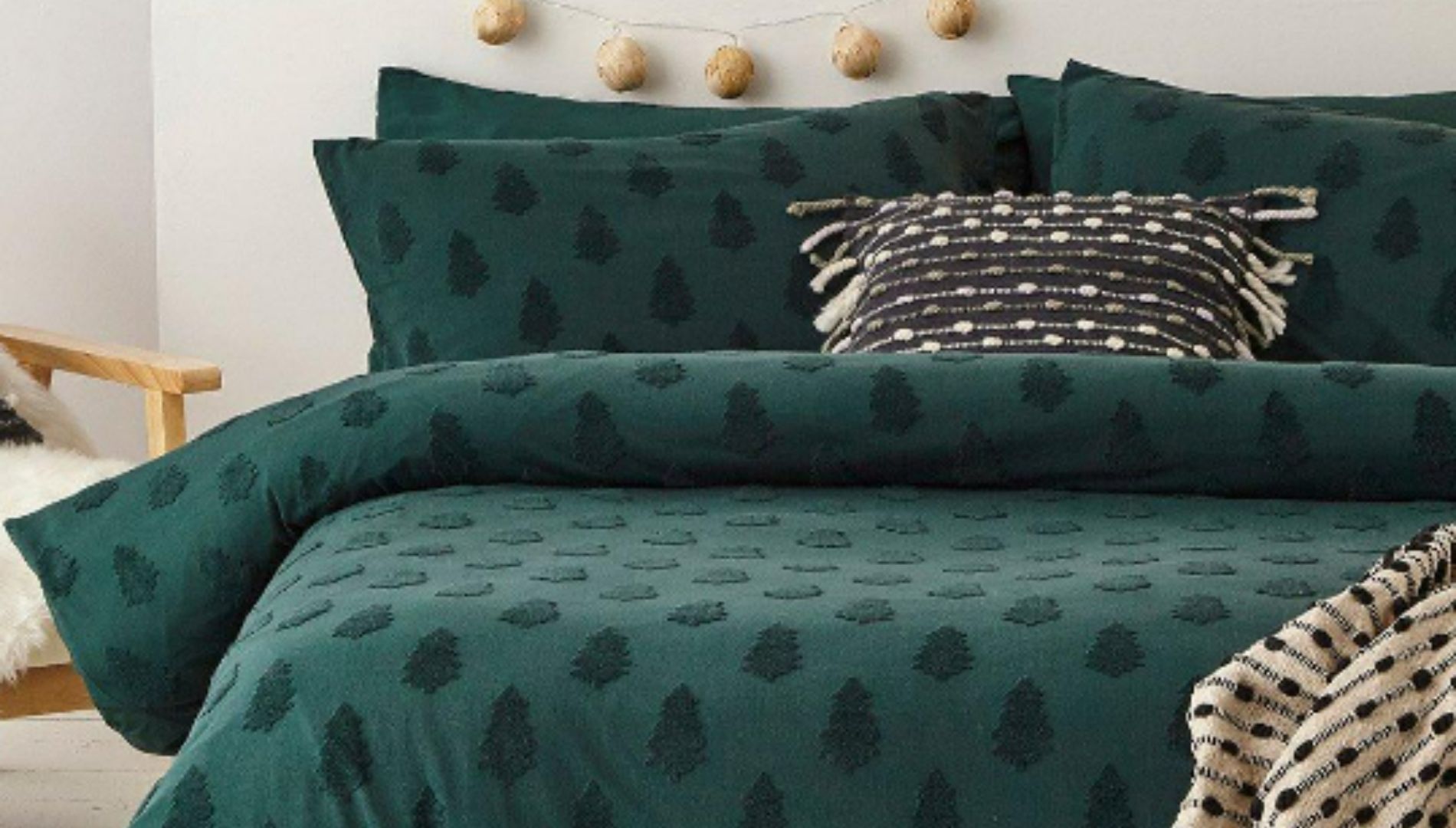 A green bedding set with a tufted tree pattern on a double bed, with pillows.