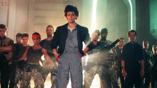 Sigourney Weaver's Ripley stands in front of her commando squad with a bright light shining behind them in Aliens