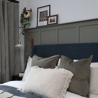 Grey bedroom with panelled wall behind bed.