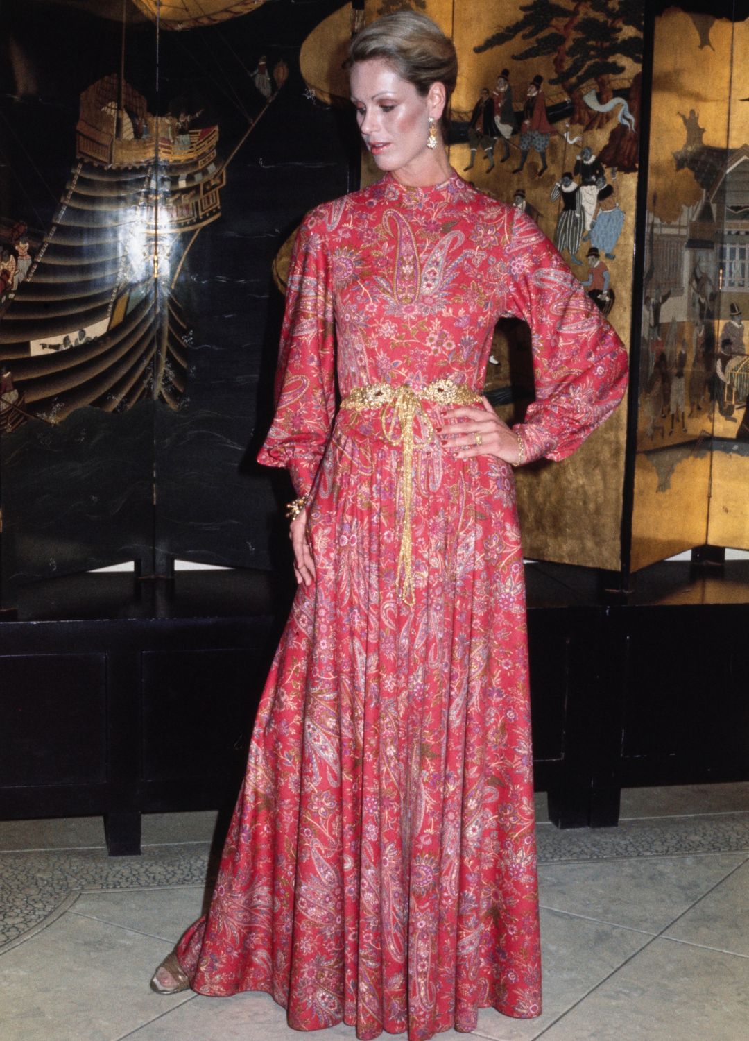 A model wearing a red evening dress from the autumn and winter collection by Jerry Silverman in New York, April 26th 1977. The dress is a Chinese-inspired red lacquer dress in paisley floral print, designed for informal evening wear. Silverman's designer, Shannon Rodgers, owns a collection of 17th, 18th and 19th century Chinese robe