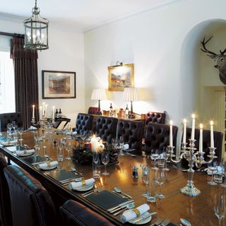 dinning room with brown dinning table brown chairs white wall and candle with stand on table