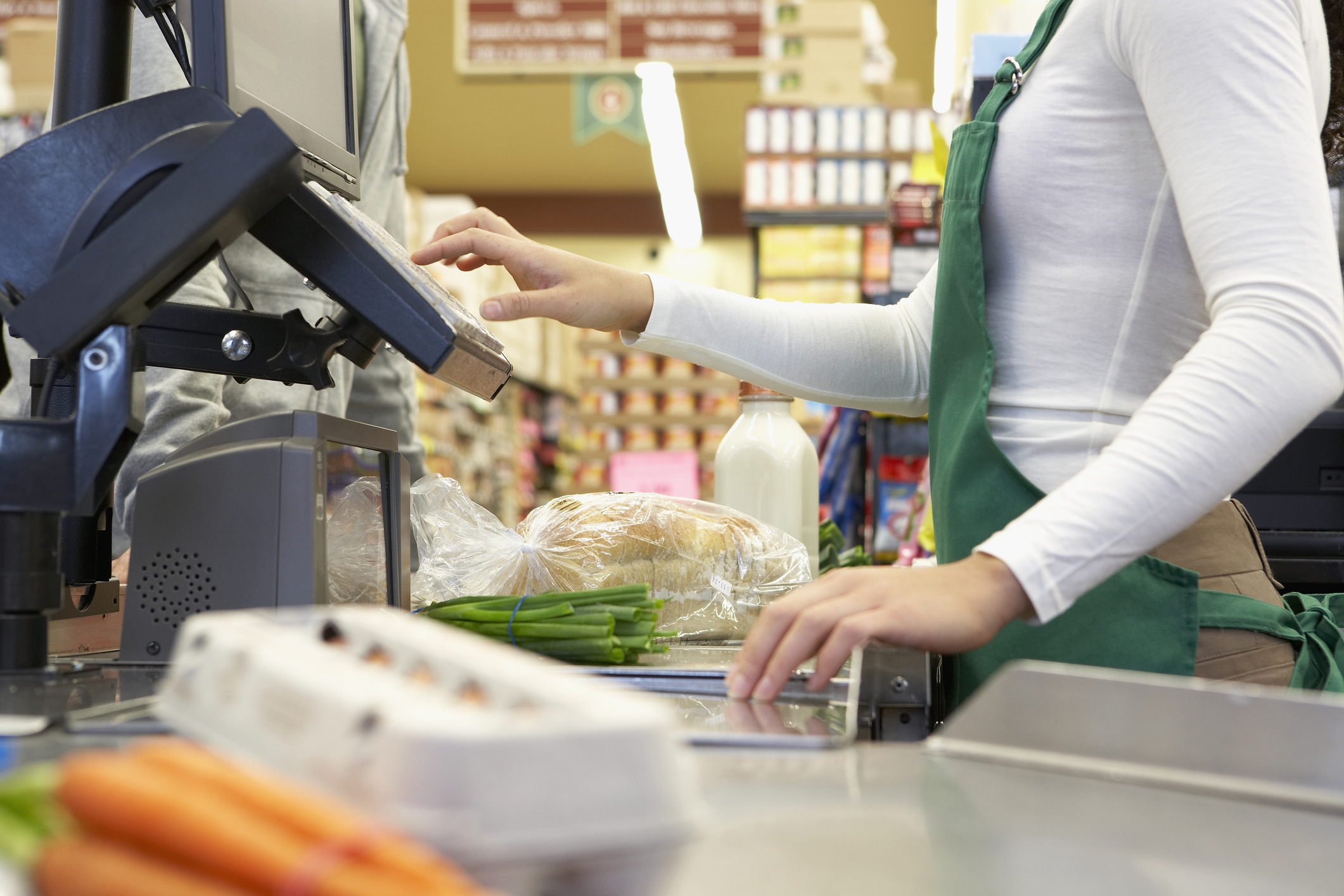 Cajero deslizando comestibles a través de un sistema POS