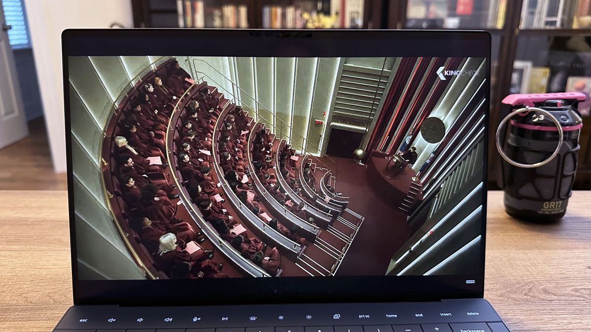 A movie trailer playing on a Dell XPS 13 (9350) that is sitting on a wooden desk.