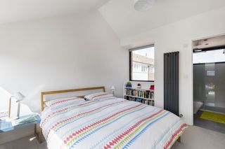 white bedrrom with patterned bedding, a vertical radiator and an ensuite