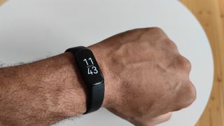 En man med en svart Fitbit Luxe runt handleden som visar tiden.
