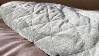 Mela Original Weighted Blanket review: an image of the blanket in grey placed on our bed during testing