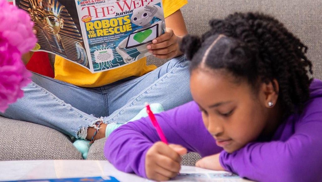 A young girl reading The Week Junior