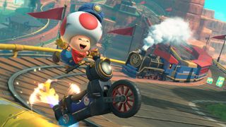 Mario Kart World screenshot showing Toad racing on a bike with a train in the distance.