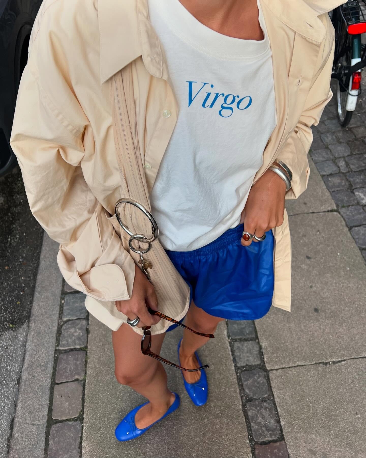 @amalienielsenn wearing a Virgo graphic tee, button-down, and athletic shorts.