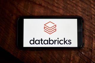 Databricks logo displayed on a smartphone screen with brown wooden background