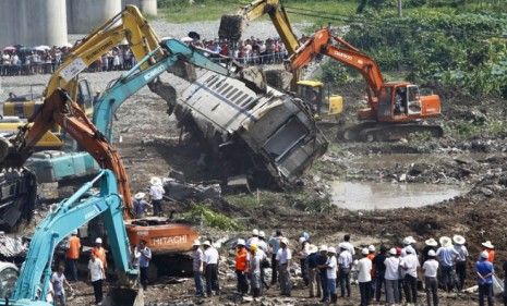 Excavators dig through wreckage