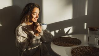 Woman drinking a cup of tea in morning light