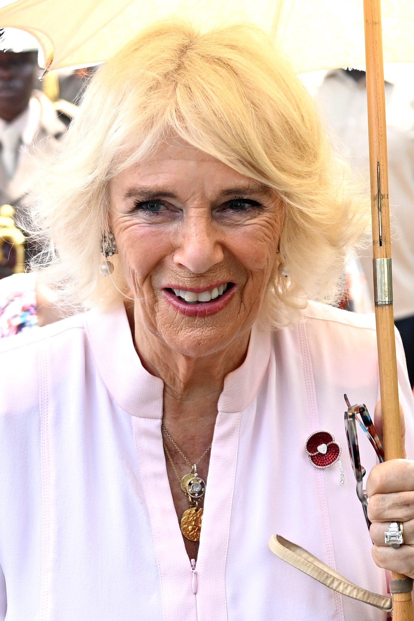 Queen Camilla wearing a pink coat holding an umbrella