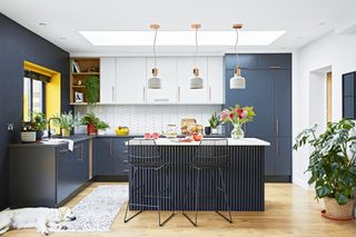 Dark blue kitchen with white wall units and splashback and slatted panel island