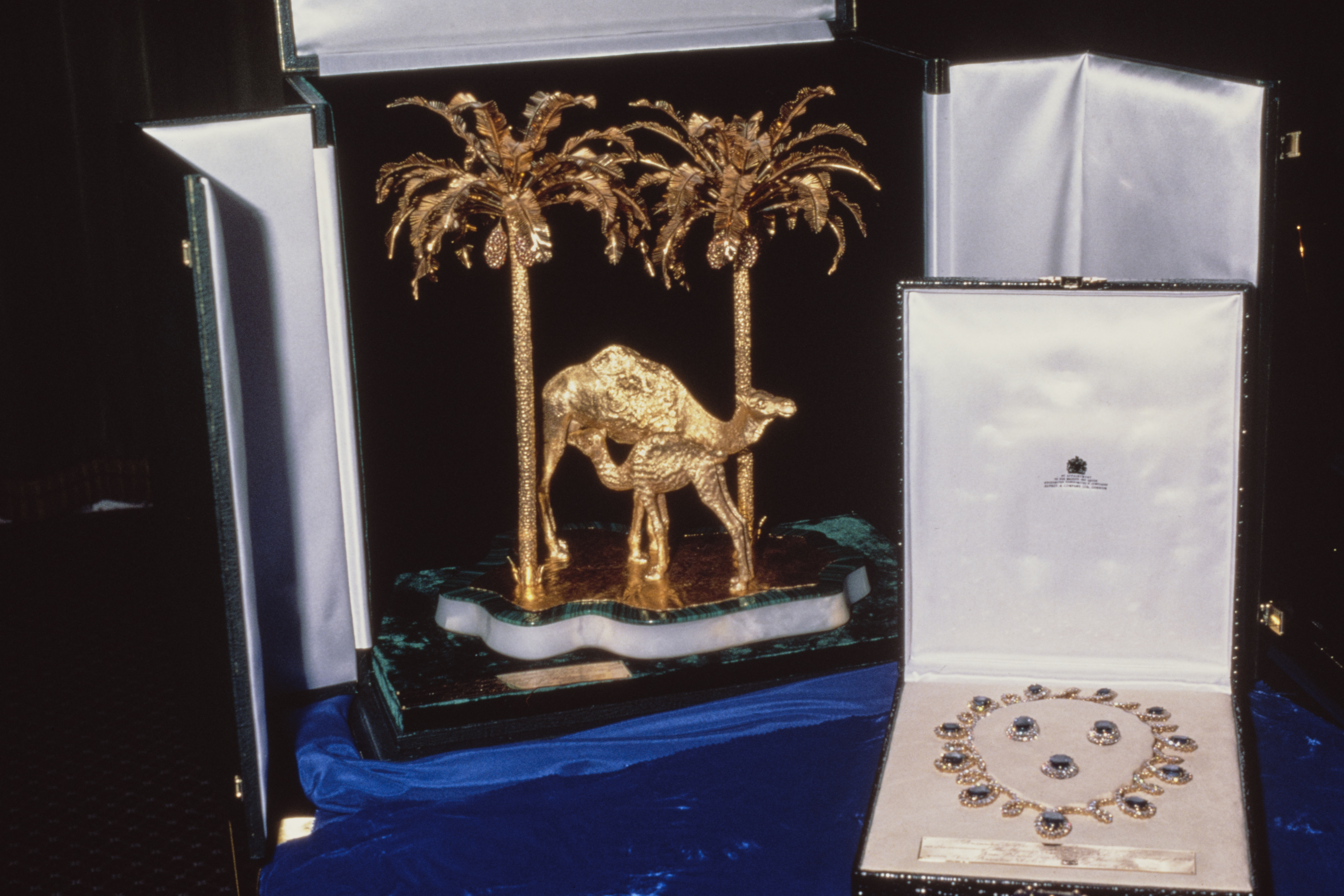 A gold camel statue next to a box with a sapphire necklace and earrings