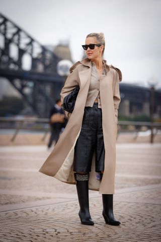 woman wearing trench coat, cardigan, bermuda shorts, and boots