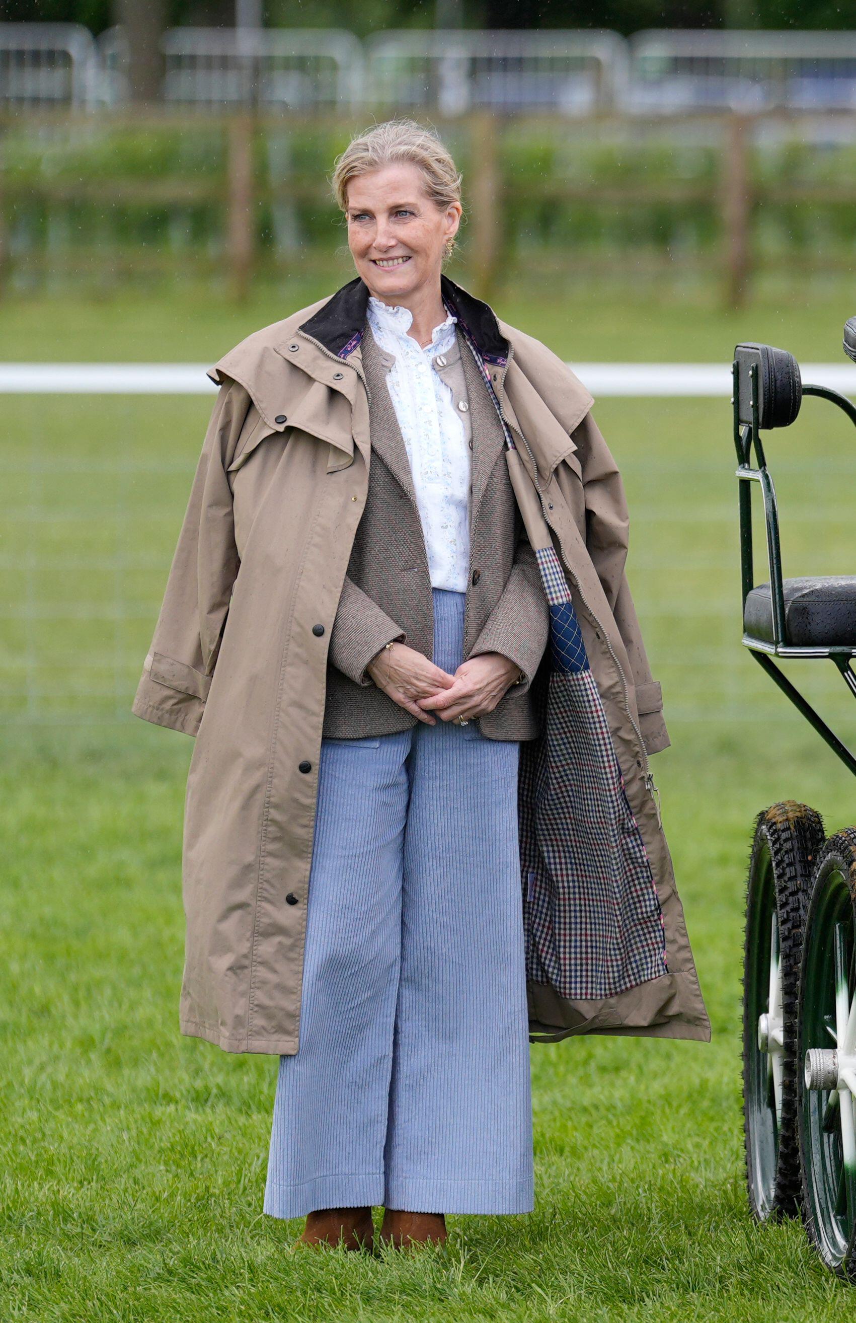 Duchess Sophie wearing blue pants and a coat smiling in grass