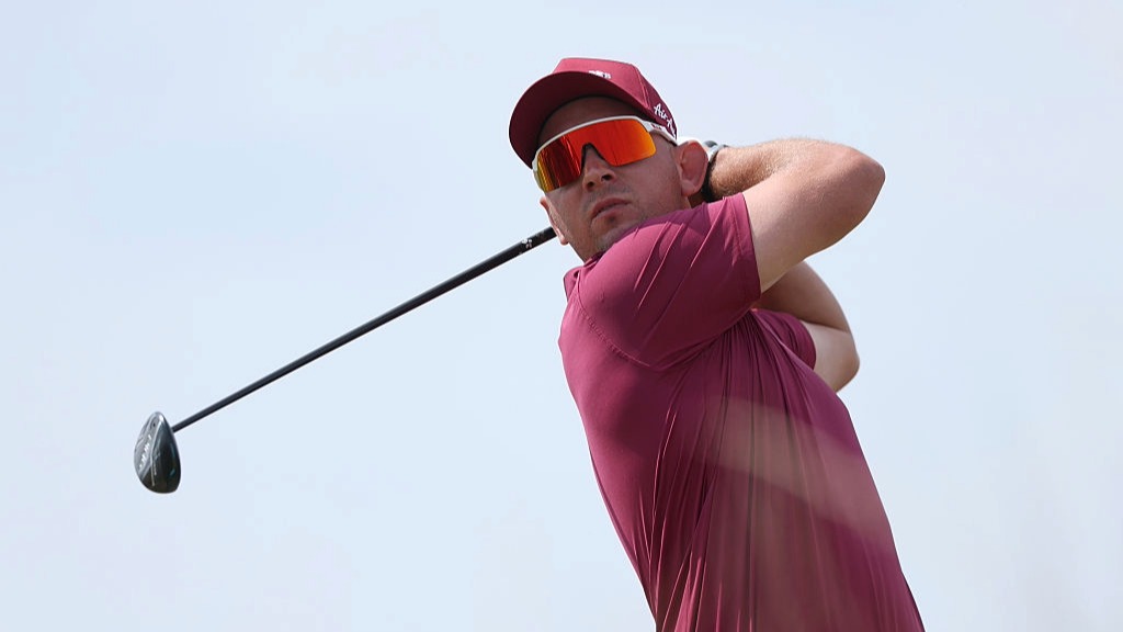Lucas Herbert, wearing red, plays a shot at the Open 2026