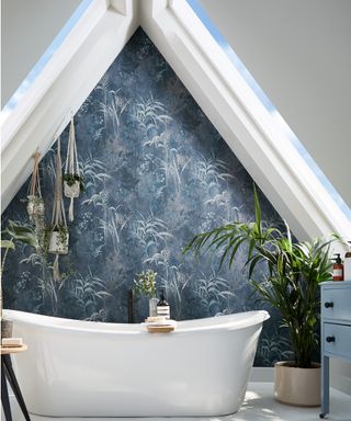 A blue loft bathroom idea with printed wallpaper and freestanding white bathtub