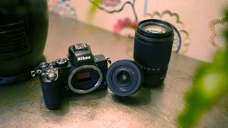 The Nikon Z50 sits on a surface with two lenses