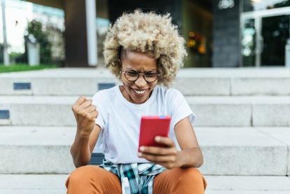 Excited young woman receiving good news on her mobile phone