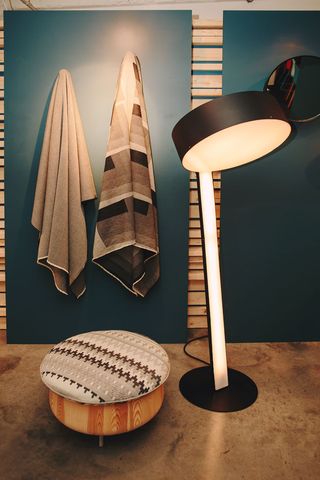 Two patterned towels hanging on a dark blue wall beside a lamp