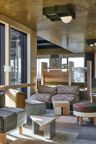 A hotel lobby with coloful patchwork bohemian patterned seating, large windows and industrial style lighting