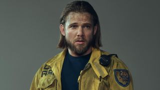 Max Thieriot posing for a character photo in a yellow Cal Fire jacket for Fire Country Season 3. 