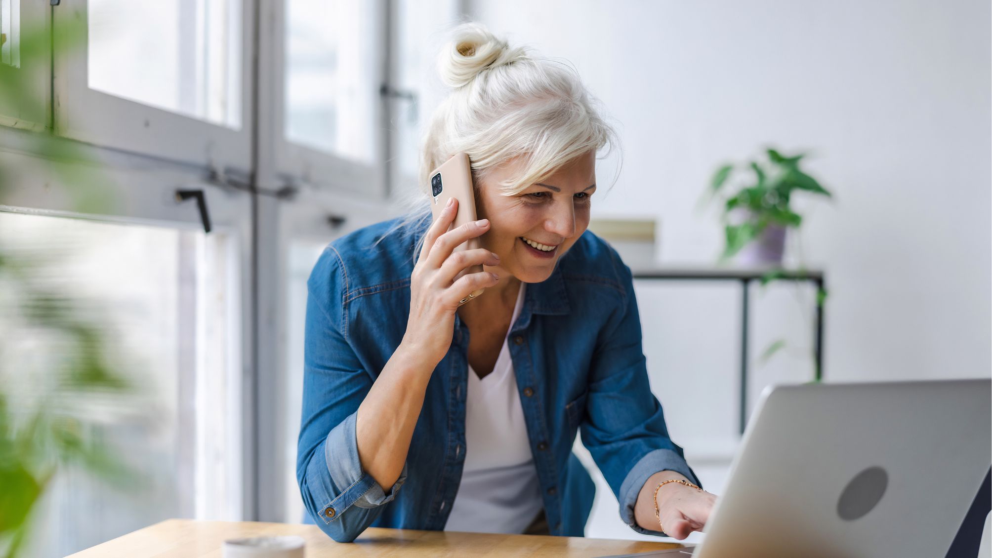 A woman talking on mobile phone while using laptop in office