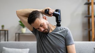 Person using a massage gun to alleviate back pain