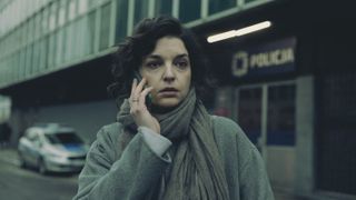 Greta looking stressed and on the phone standing outside the police station in Just One Look